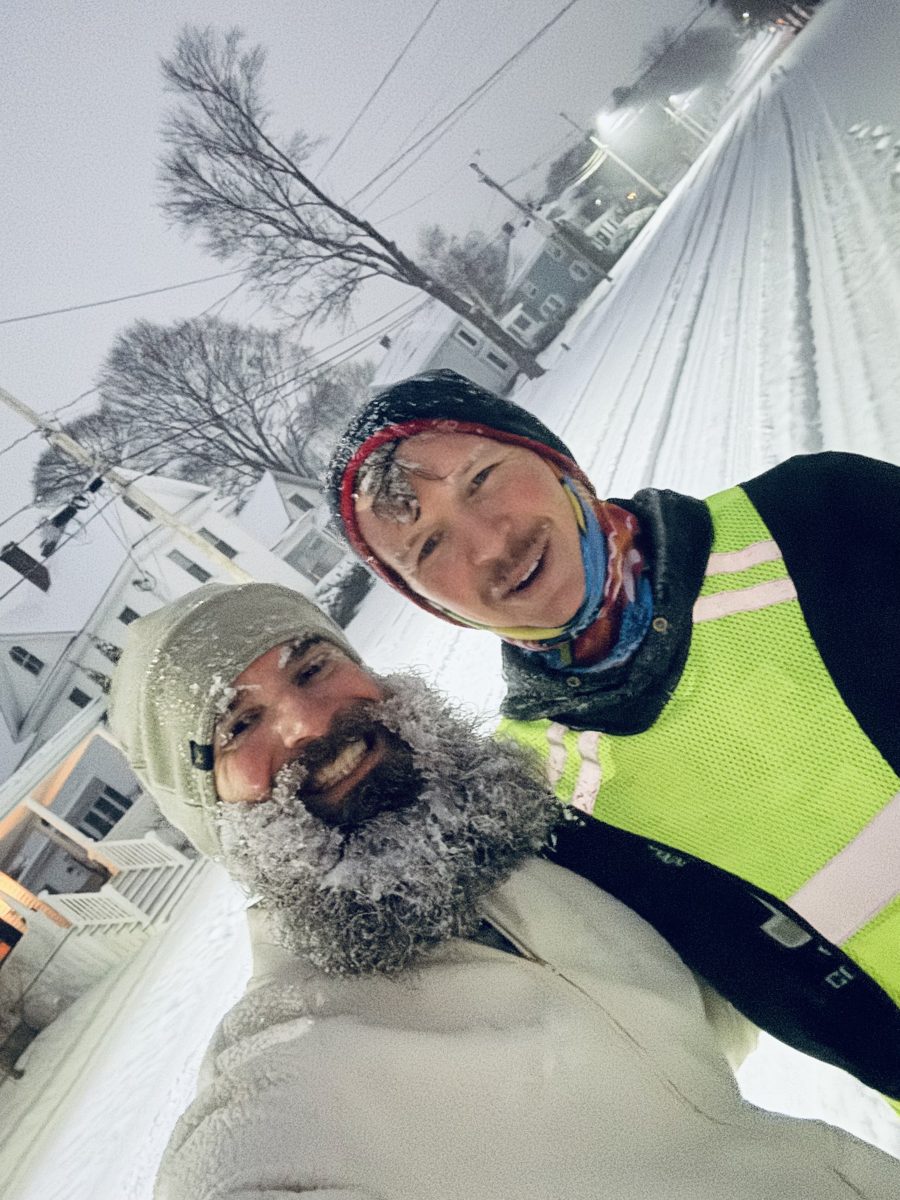 Two runners on a snowy Bangor street, one in the B.A.D Crew beanie